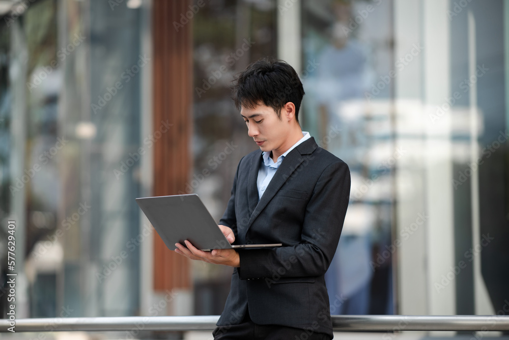 Asian businessman using a tablet and laptop on a bench in the city Asian businessman using a tablet and laptop on a bench in the city
