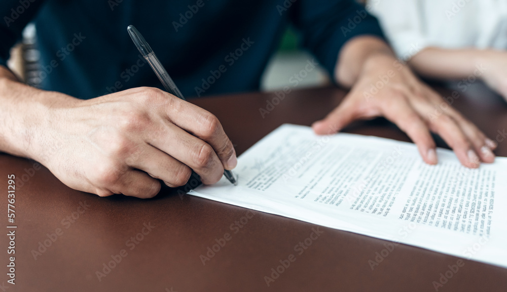 Man hand signing bank loan agreement with real-estate agent to buying the house in the office. Man hand signing bank loan agreement with real-estate agent to buying the house in the office.