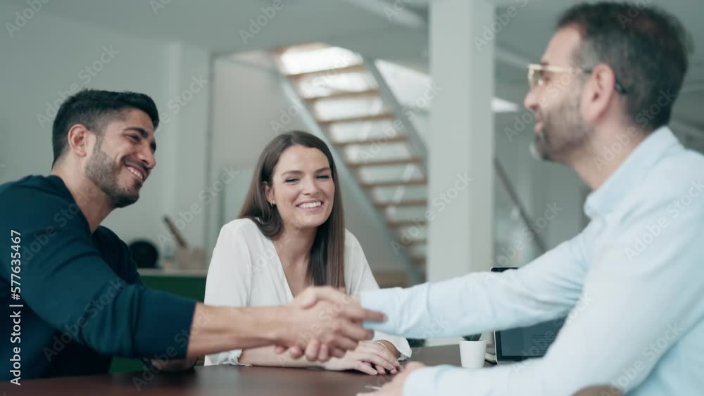 Video of attractive real-estate agent shaking hands with young couple after signing agreement contract in the office. Video of attractive real-estate agent shaking hands with young couple after signing agreement contract in the office.