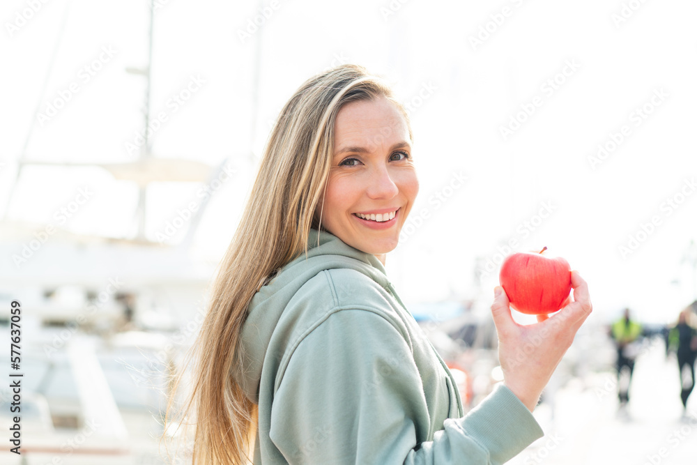 Young blonde woman with an apple at outdoors Young blonde woman with an apple at outdoors