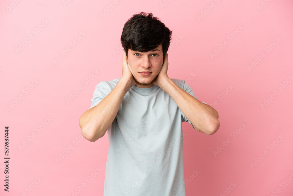 Young Russian man isolated on pink background frustrated and covering ears