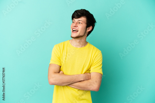 Young Russian man isolated on blue background happy and smiling