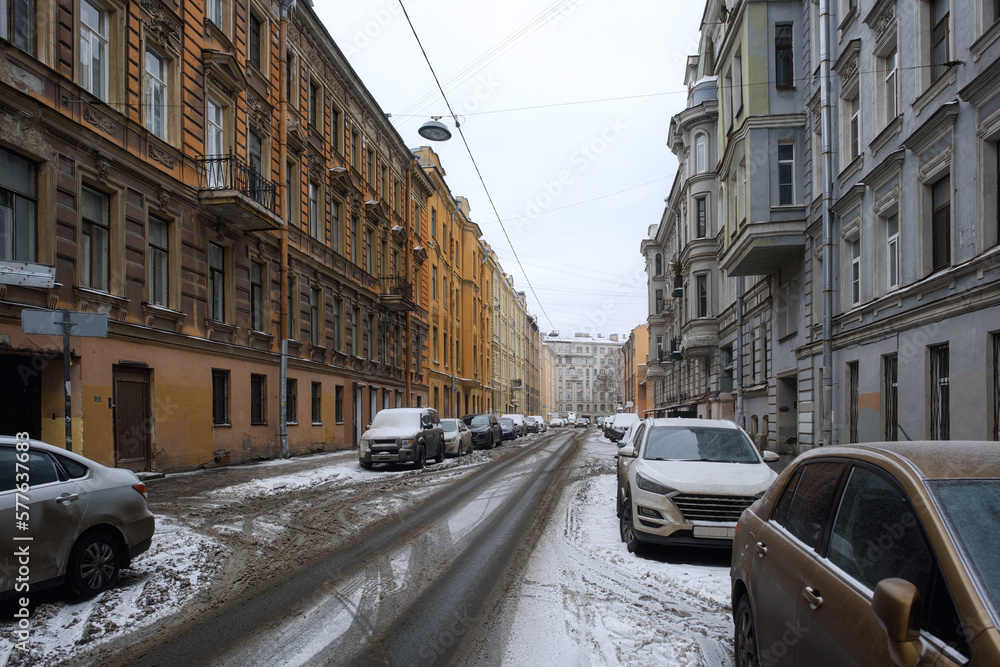 Old street of St. Petersburg with parked cars. Snow porridge on the roads of the city.