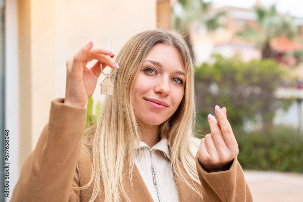 Young pretty blonde woman holding home keys at outdoors Young pretty blonde woman holding home keys at outdoors