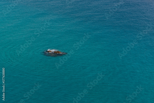 Scoglio isolato in mezzo al mare blu con onde concentriche tutt'attorno © fulviodegregorio