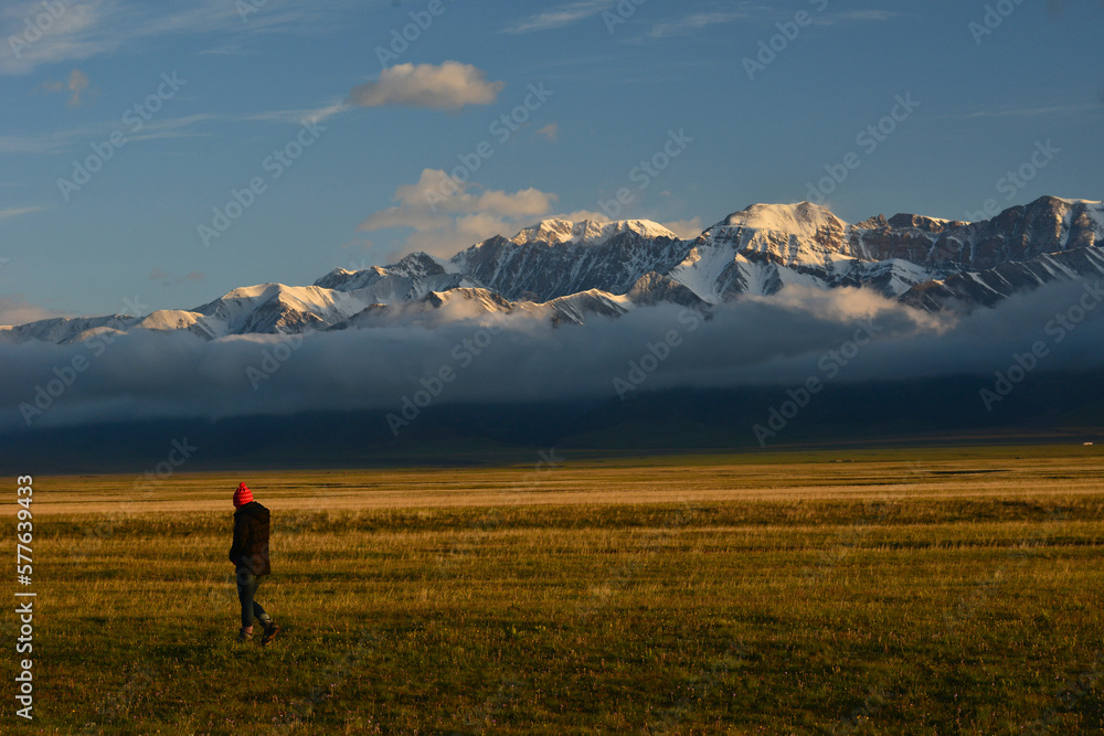 On the bank of Sayram Lake Lake in Xinjiang in the chilly early morning, the sun shines on the snow-capped peaks and golden grasslands. High-quality photo