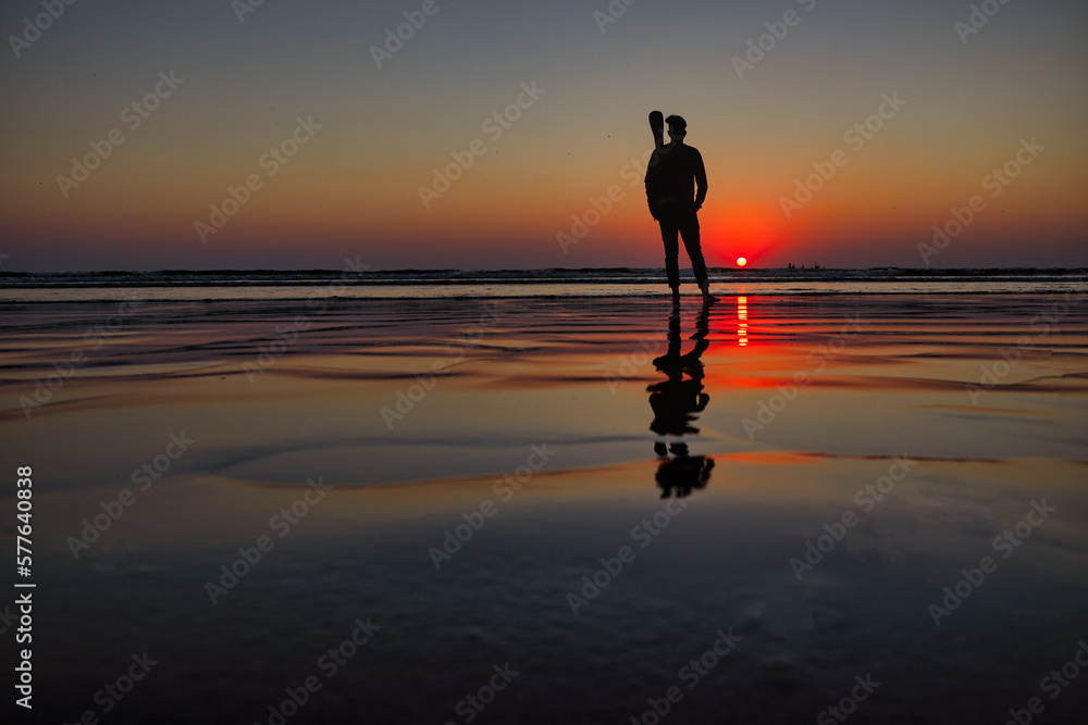 Silhouette of a woman on the beach at sunset, reflection in water. Silhouette of a woman on the beach at sunset, reflection in water.