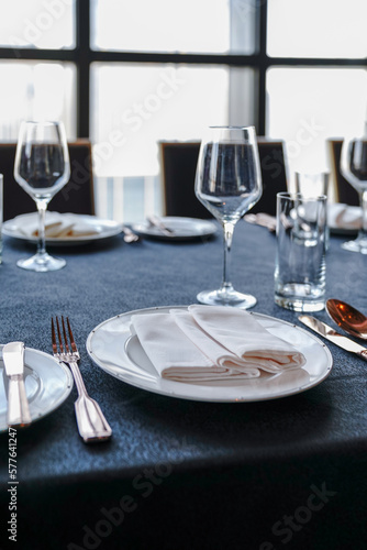 The western dining room is decorated with red wine glasses, white disks and silver-paper knives and forks.