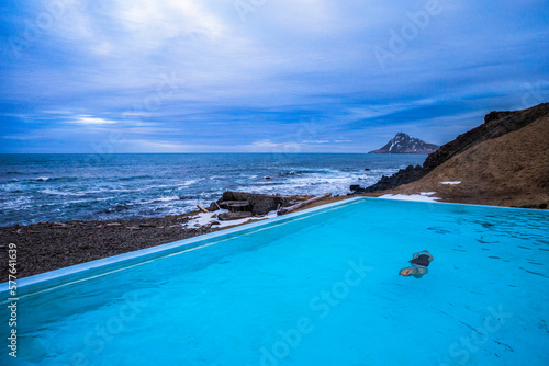 A woman swiming in a geo thermal heated pool on the beach near Nordurfjordur, Iceland