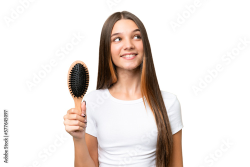 Teenager caucasian girl with hair comb over isolated background looking up while smiling