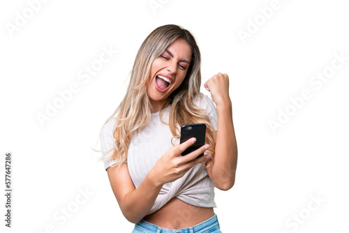 Young Uruguayan woman over isolated background with phone in victory position