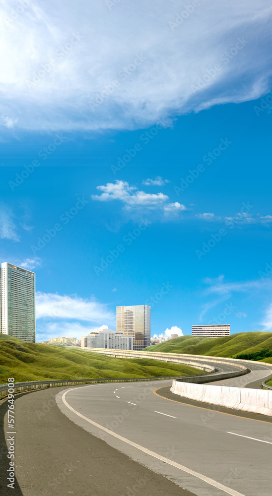 Fototapeta premium Asphalt road with green grass and cityscape