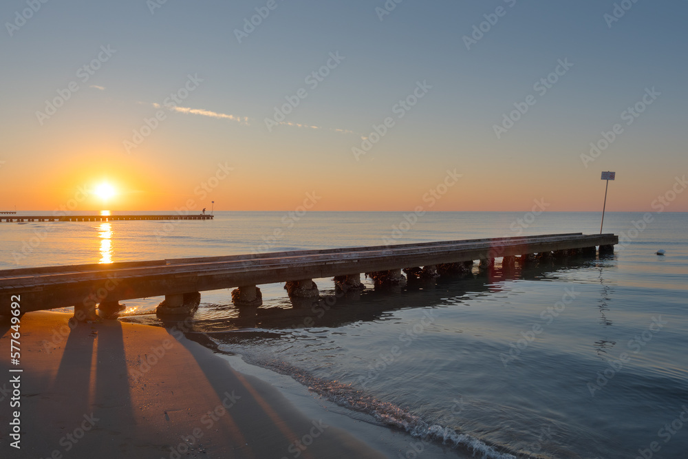 view of the rising sun on the beach with a pier