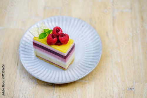 Rainbow raspberry cheesecake on white plate on wooden table