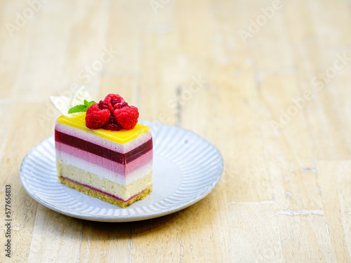 Rainbow raspberry cheesecake on white plate on wooden table