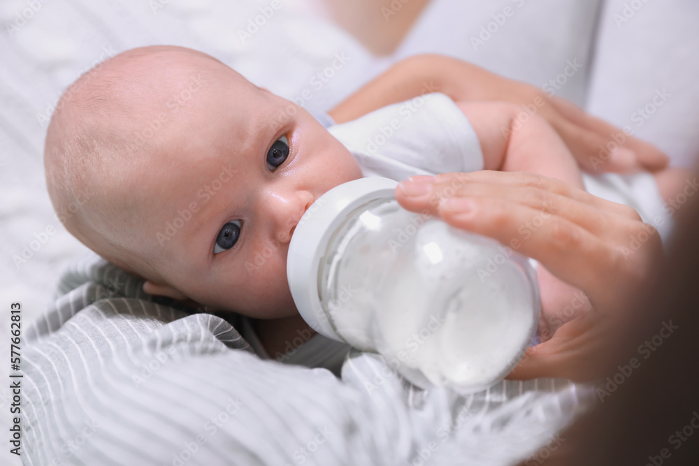 Mother feeding her little baby from bottle, closeup Mother feeding her little baby from bottle, closeup