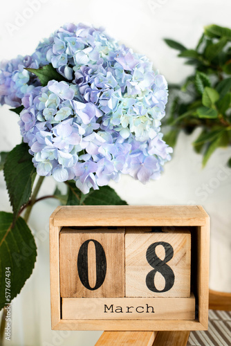 Close up a wooden calendar blocks with the date March 8 on a blue hydrangea background. International Women's Day holiday concept