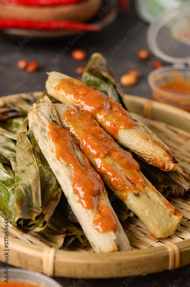 Otak-otak Tengiri with Peanut Sauce, Made from Fish and Flour, Wrap with Banana Leaves and Grill, on Wooden Table