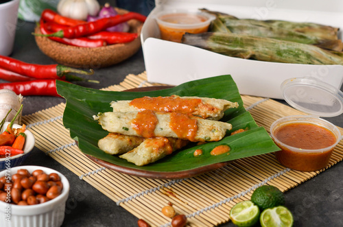 Otak-otak Tengiri with Peanut Sauce, Made from Fish and Flour, Wrap with Banana Leaves and Grill, on Wooden Table