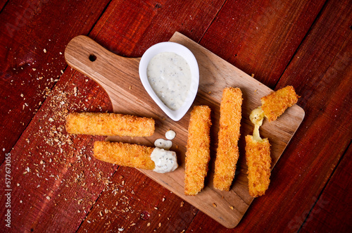 A mozzarella cheese stick served with sauce isolated on wooden background
