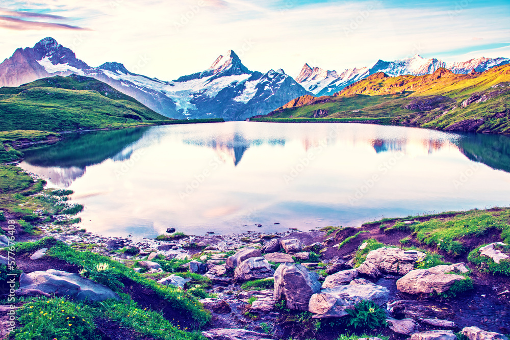 Fantastic landscape at sunrise with stones in the foreground on the lake in the Swiss Alps. Wetterhorn, Schreckhorn, Finsteraarhorn et Bachsee. Exciting places. (relaxation, harmony - concept).