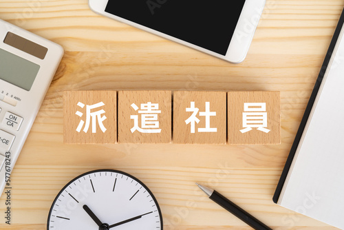 Fotografie 派遣社員と書かれたブロック、電卓、スマホ、ノート