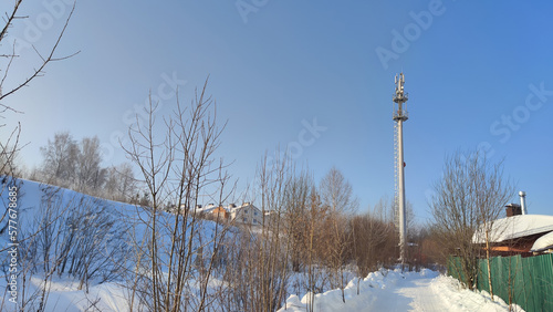 TV or cell tower in the snow at the village in cold winter day with blue sky © keleny