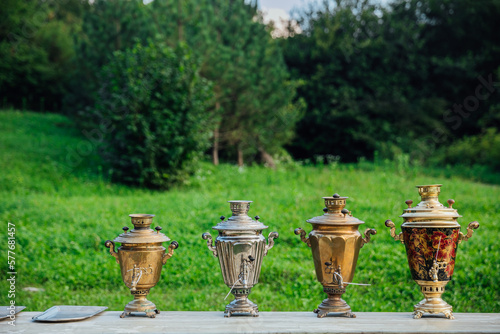 Exhibition of old-fashioned iron samovars. Bronze samovar outdoors in the forest