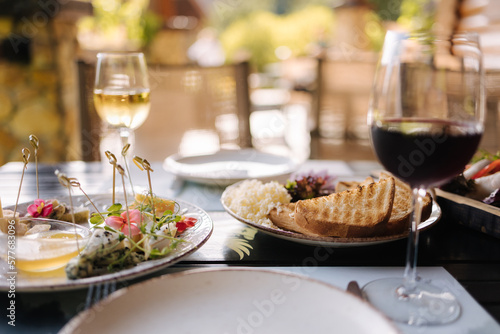 Salmon tartare served with grated butter and roasted bread. Glass of dry wine. Table with food on terrace