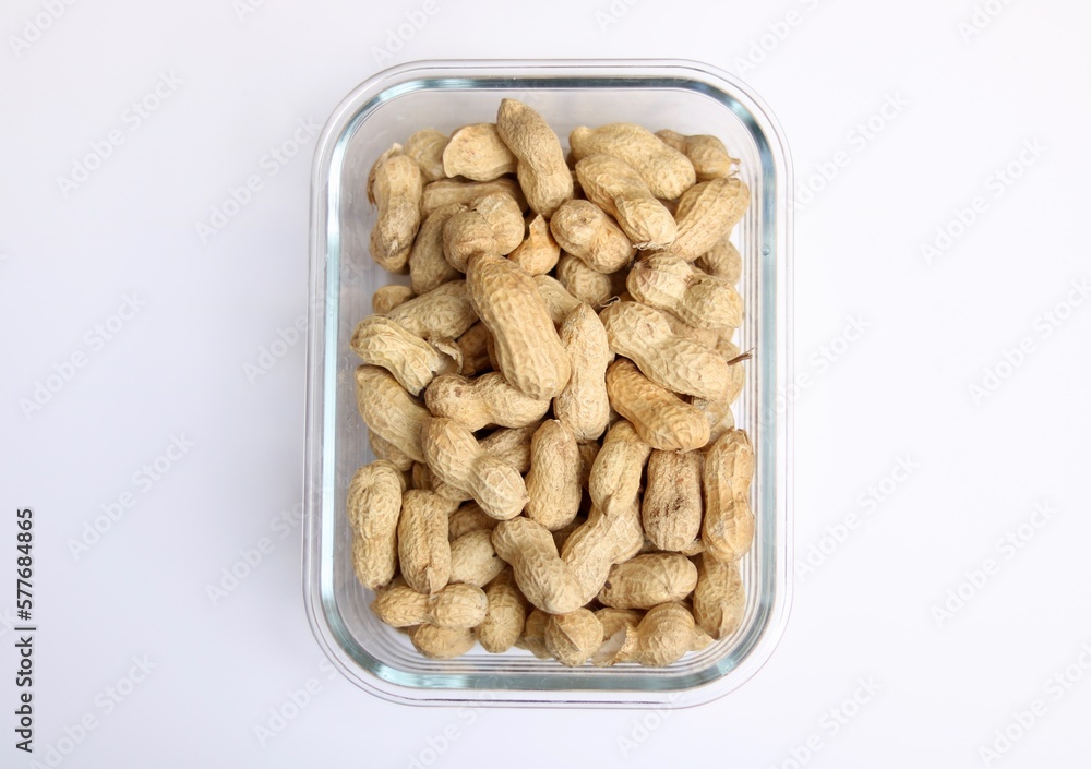 Glass dish of peanuts or monkey nuts against plain white background Glass dish of peanuts or monkey nuts against plain white background
