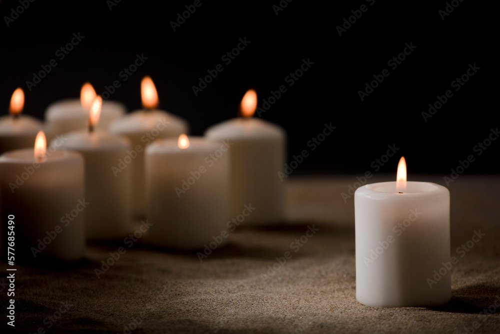 bullying concept, composed by group of lit candles, on sand with black night background bullying concept, composed by group of lit candles, on sand with black night background