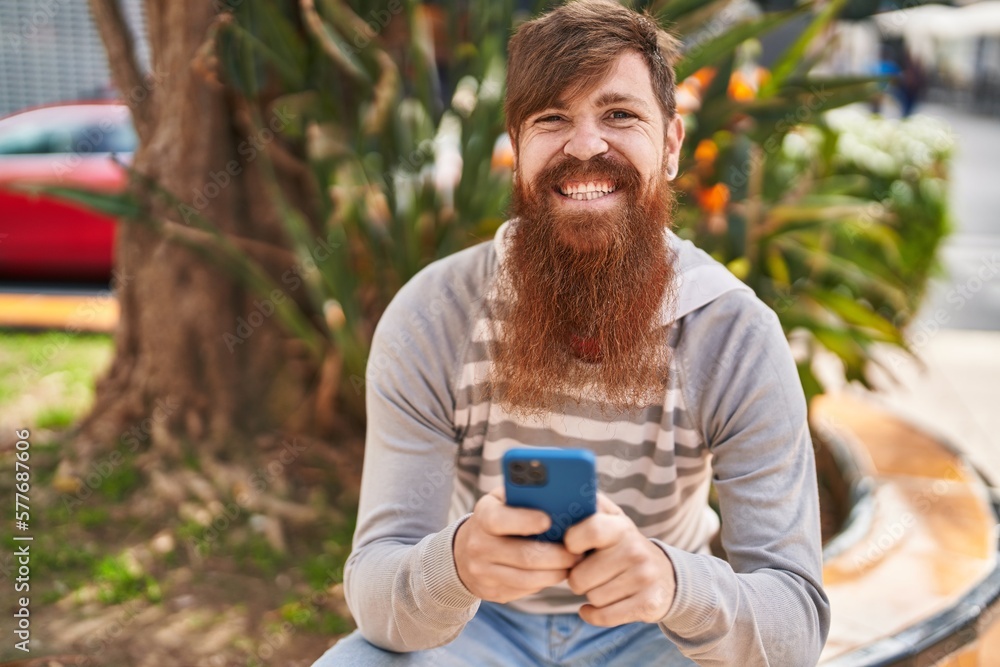 Young redhead man using smartphone sitting on bench at park Young redhead man using smartphone sitting on bench at park