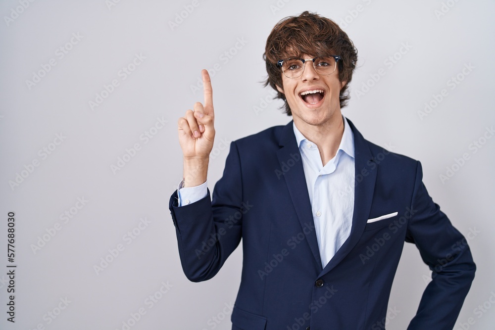 Hispanic business young man wearing glasses pointing finger up with successful idea. exited and happy. number one. Hispanic business young man wearing glasses pointing finger up with successful idea. exited and happy. number one.