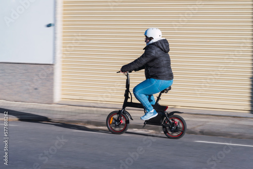 40 year old woman riding her electric scooter through the streets of the city (Concept of electric mobility)
