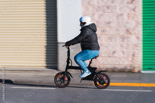 40 year old woman riding her electric scooter through the streets of the city (Concept of electric mobility)