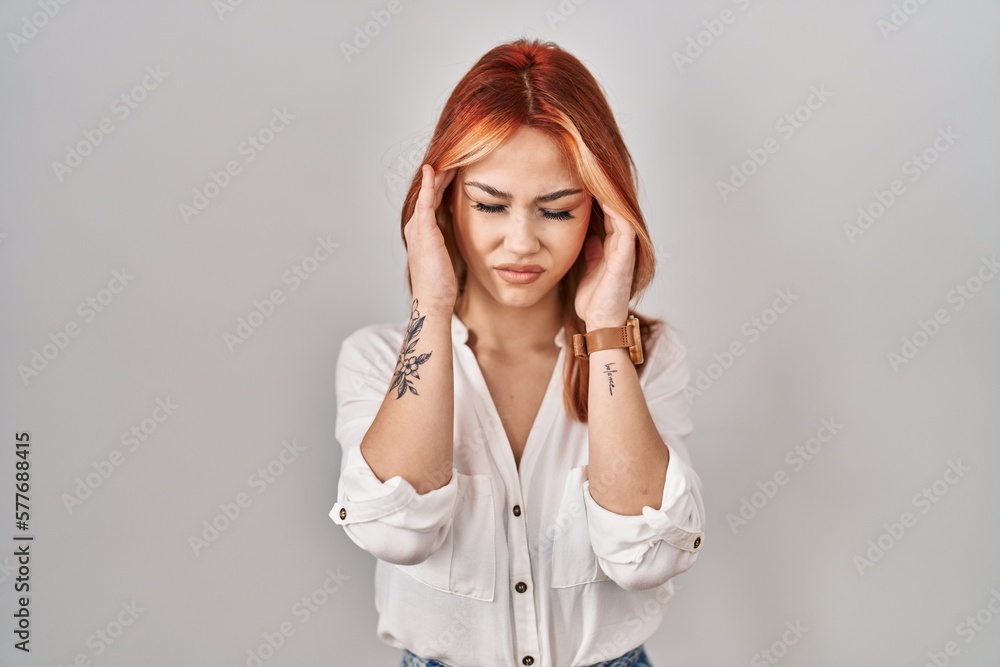 Young caucasian woman standing over isolated background with hand on head, headache because stress. suffering migraine. Young caucasian woman standing over isolated background with hand on head, headache because stress. suffering migraine.