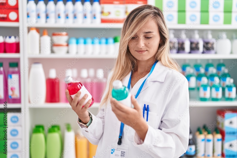 Young blonde woman pharmacist smiling confident holding medication bottles at pharmacy Young blonde woman pharmacist smiling confident holding medication bottles at pharmacy