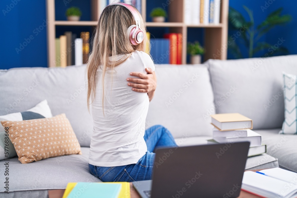 Young blonde woman studying using computer laptop at home hugging oneself happy and positive from backwards. self love and self care Young blonde woman studying using computer laptop at home hugging oneself happy and positive from backwards. self love and self care