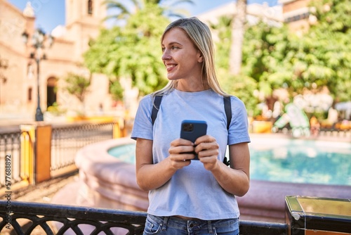 Young blonde woman smiling confident using smartphone at park