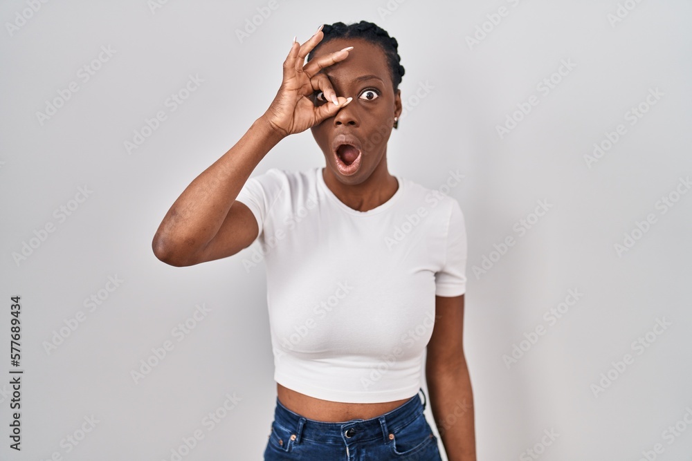 Beautiful black woman standing over isolated background doing ok gesture shocked with surprised face, eye looking through fingers. unbelieving expression. Beautiful black woman standing over isolated background doing ok gesture shocked with surprised face, eye looking through fingers. unbelieving expression.