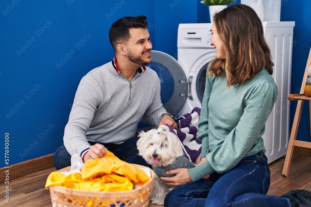 Man and woman washing clothes with dog at laundry room Man and woman washing clothes with dog at laundry room