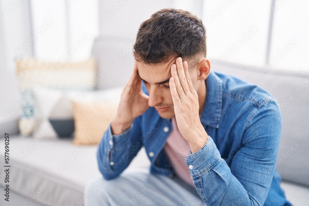 Young hispanic man stressed sitting on sofa at home Young hispanic man stressed sitting on sofa at home