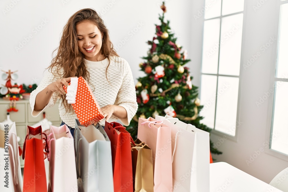 Young beautiful hispanic woman smiling confident holding christmas gift at home