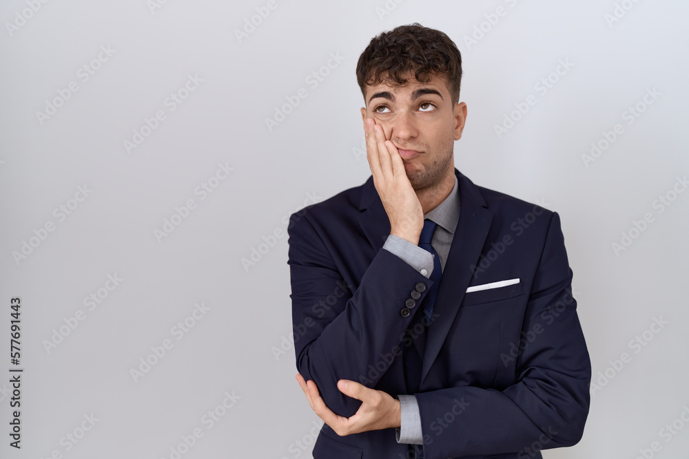 Young hispanic business man wearing suit and tie thinking looking tired and bored with depression problems with crossed arms. Young hispanic business man wearing suit and tie thinking looking tired and bored with depression problems with crossed arms.