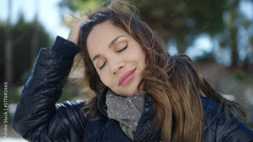 Young beautiful hispanic woman combing hair with hands at street Young beautiful hispanic woman combing hair with hands at street