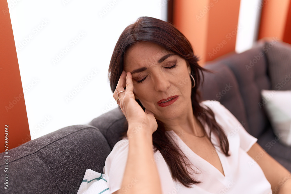 Middle age hispanic woman stressed sitting on sofa at home Middle age hispanic woman stressed sitting on sofa at home