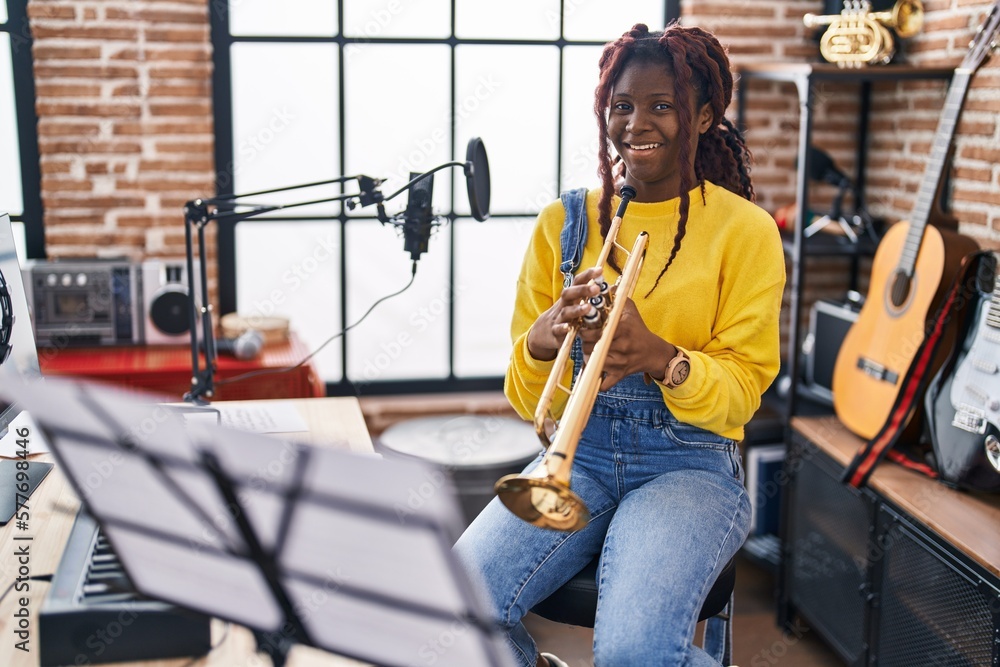 Obraz premium African american woman musician smiling confident holding trumpet at music studio