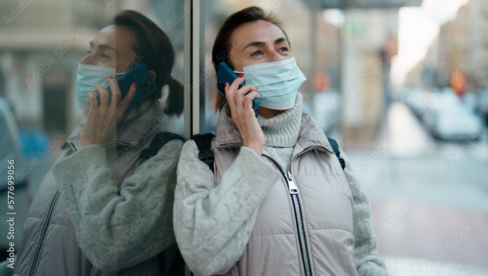 Middle age hispanic woman wearing medical mask talking on the smartphone at street Middle age hispanic woman wearing medical mask talking on the smartphone at street