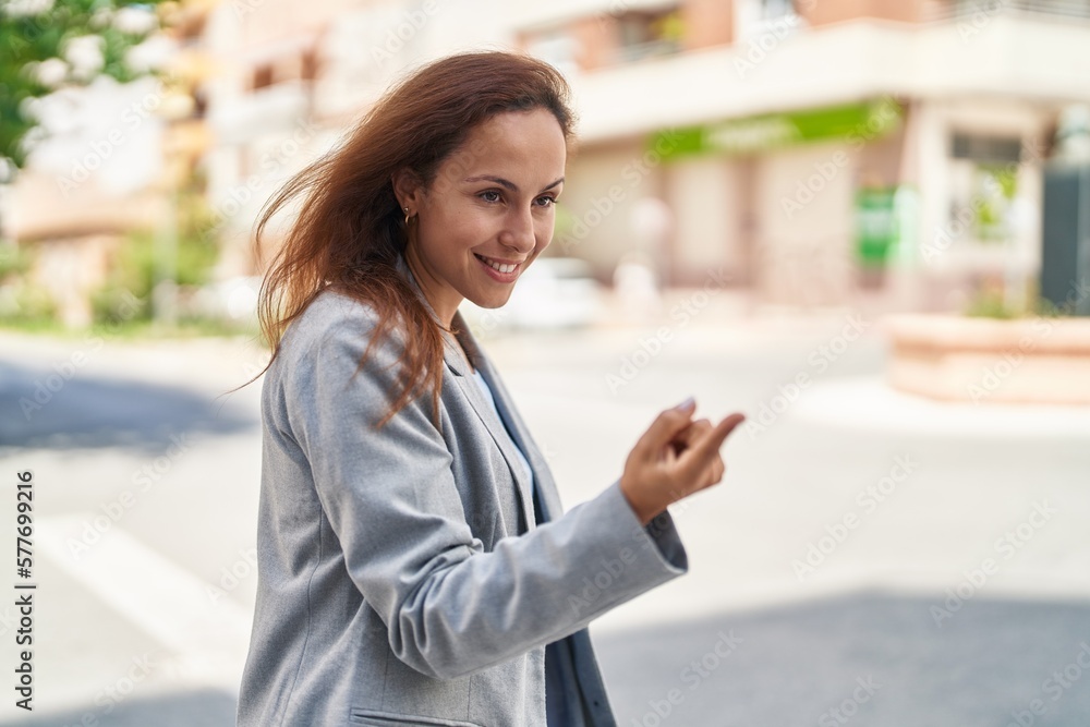 Fototapeta premium Young woman executive doing coming gesture with finger at street
