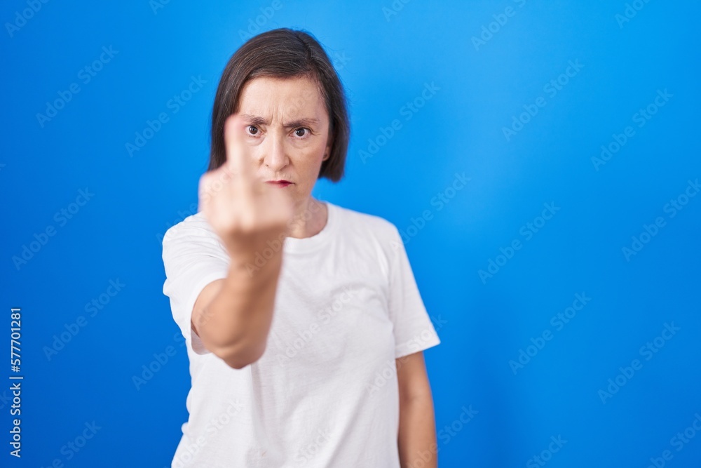 Middle age hispanic woman standing over blue background showing middle finger, impolite and rude fuck off expression Middle age hispanic woman standing over blue background showing middle finger, impolite and rude fuck off expression